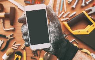 Handwerker App auf Smartphone in Hand von Handwerker über Arbeitsplatte