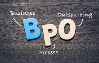 BPO: Auf einem Holztischen liegen die Buchstaben BPO, beschriftet mit "Business Process Outsourcing"
