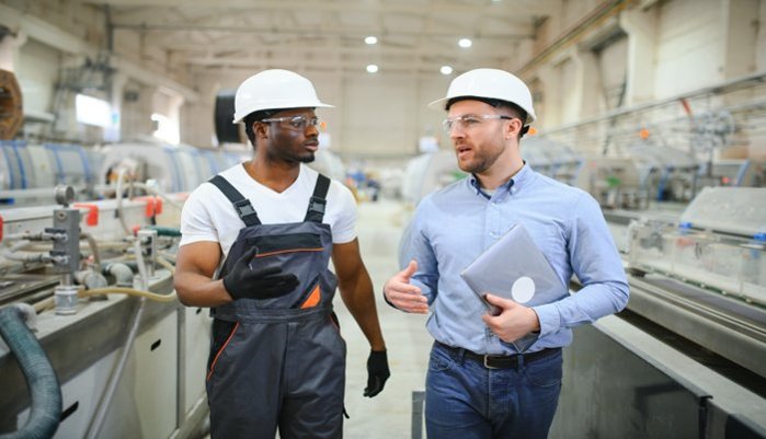 Zwei Fachkräfte bei der Prüfung einer Maschine mit einer Maschinenabnahme-Checkliste.