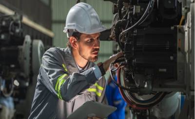 Techniker überprüft digitale Rüstanweisungen an Maschinensteuerung in einer Produktionshalle.