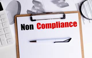 okument mit der Aufschrift 'Non Compliance' als Symbol für Compliance Verstöße und Compliance Probleme in Unternehmen.
