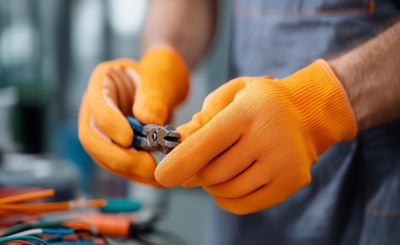 Wartungsarbeiten an Kabeln mit Zange und Schutzhandschuhen
