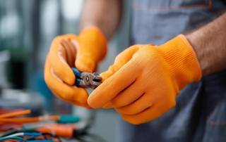 Wartungsarbeiten an Kabeln mit Zange und Schutzhandschuhen